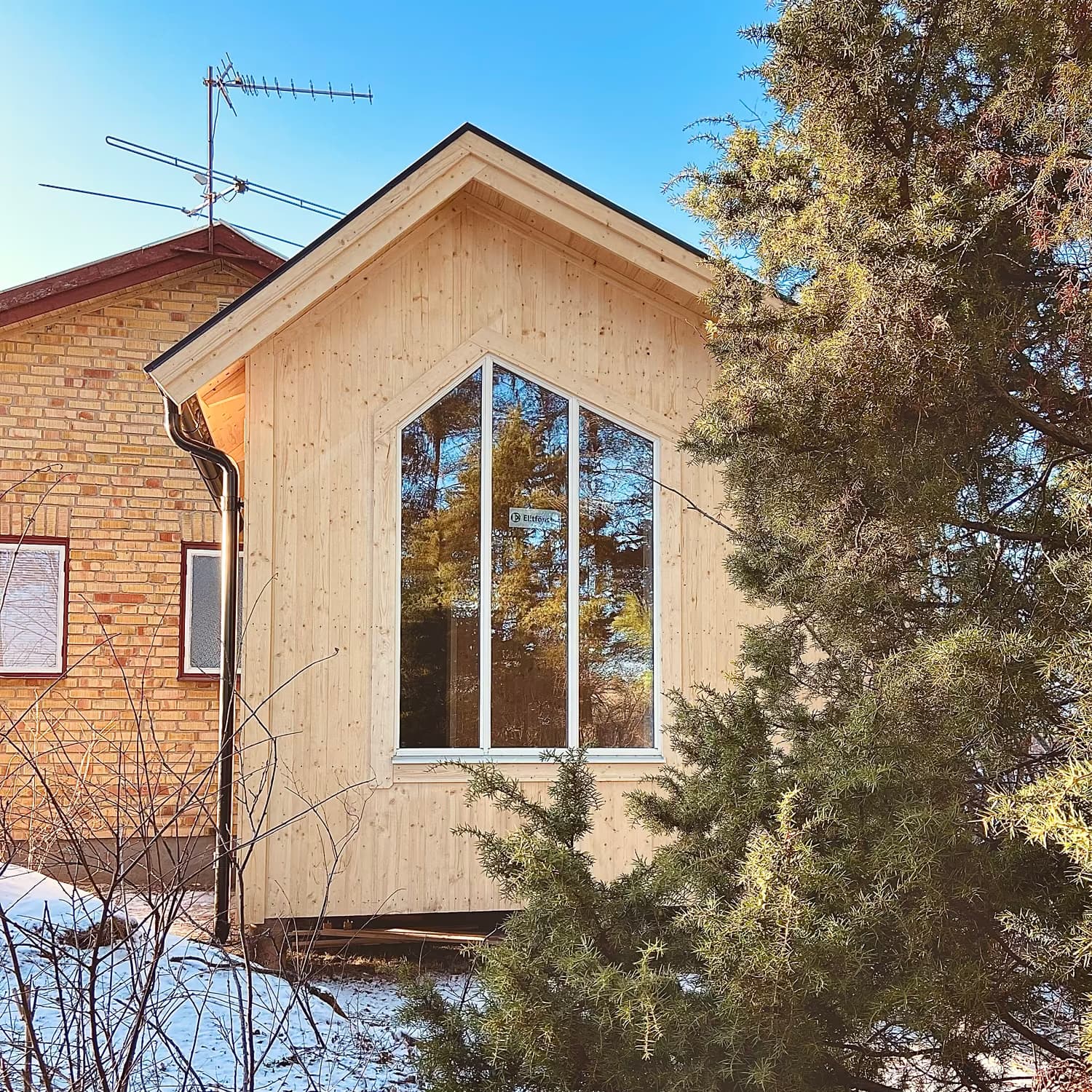Tillbyggnad i trä intill ett tegelhus